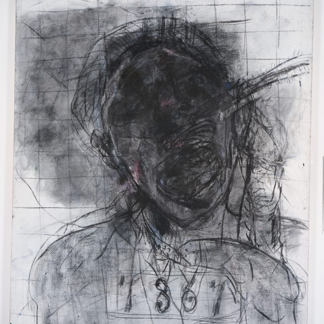 A work in charcol and oil depicting a very distorted figure from the shoulders up. The face and twisted features of the figure are obscured by dark smudging.