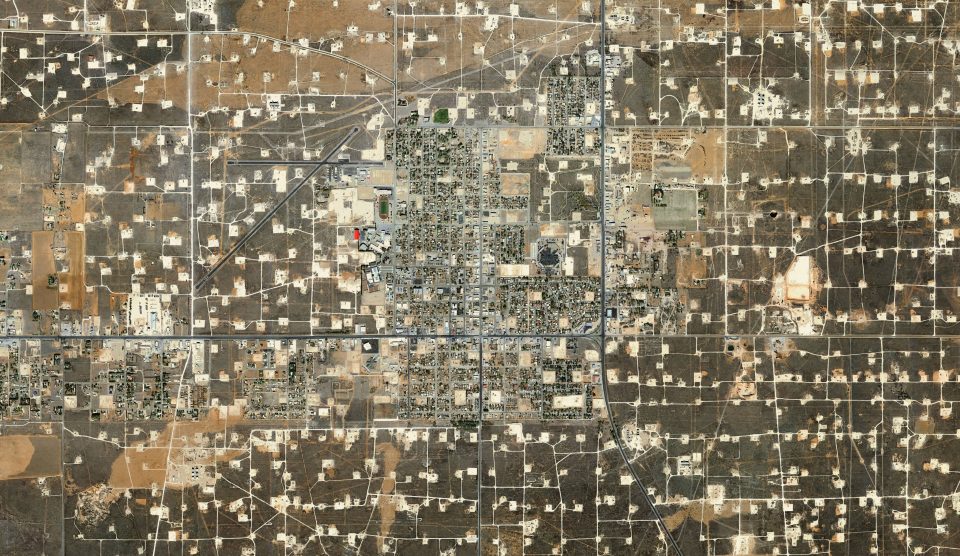 An aerial photograph showing an oil and gas facility. From this perspective it resembles a computer chip board.