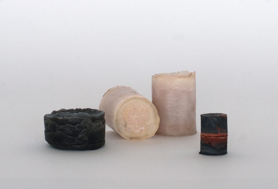 four crystalline cylinders against a white background. Two of them are black and true are beige