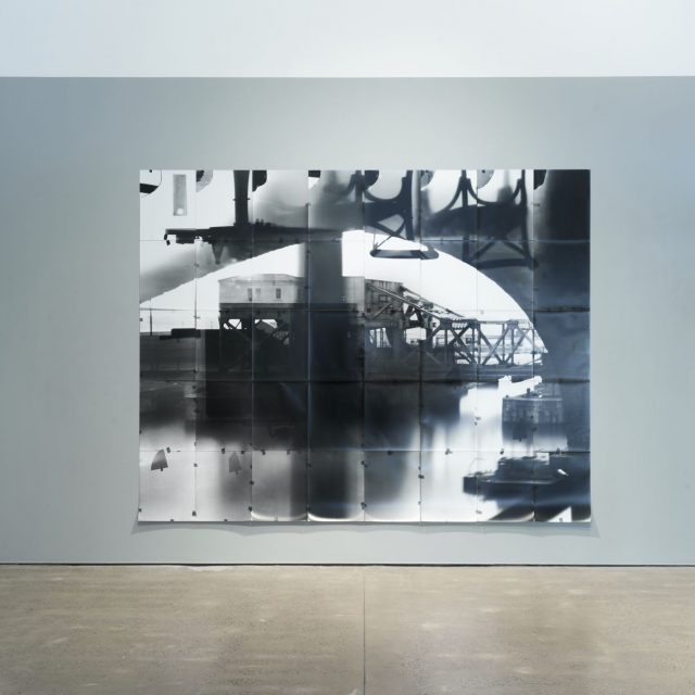 This is a black and white photo depicting some machinery on the dock outside the window.