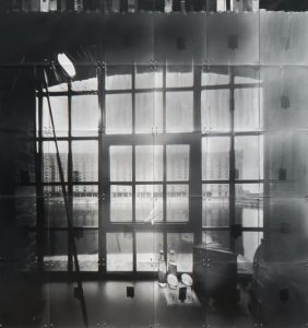 This is a black and white photo of a tall building facing the water outside the window.