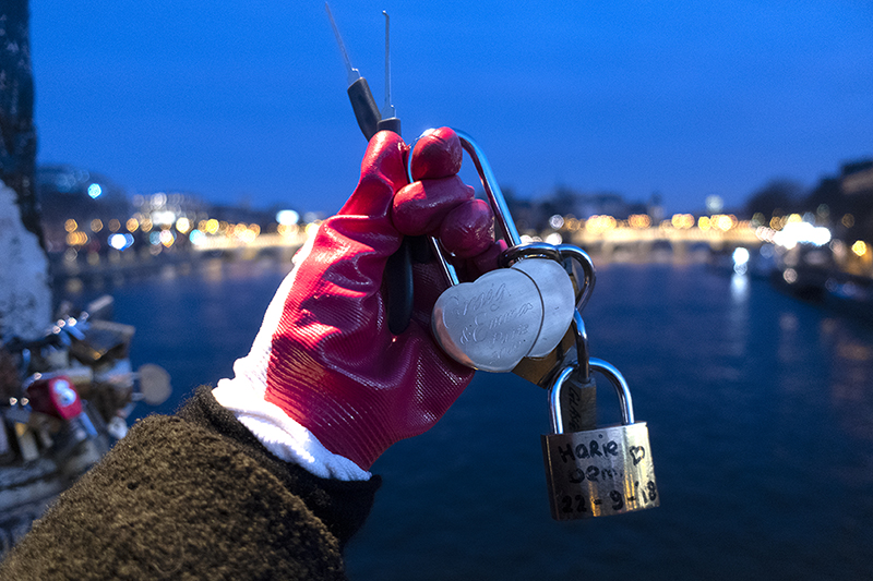 A pair of hands in red gloves holds a chain of locks.