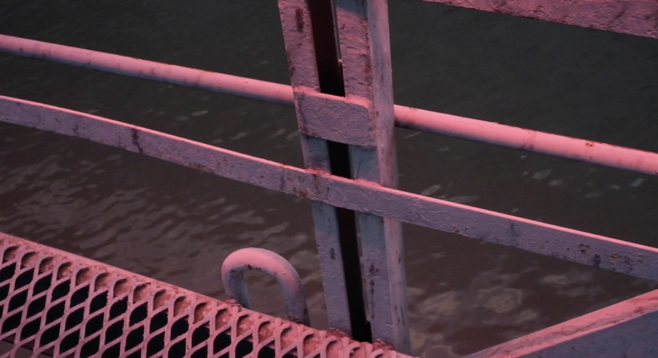 Metal fence and walkway in front of water.